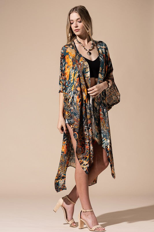 woman wearing a Lightweight Kimono
in a Mixed Paisley Pattern Print of deep teal blue, orange and beige colors, open front with slide slit. 
