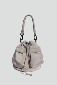 Sage nylon bucket bag with  drawstring closure, two detachable strap options (long strap, short handle) with exterior pockets in front.