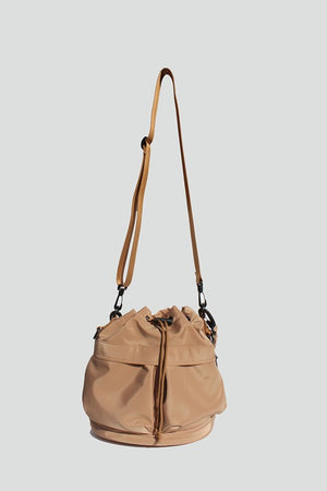 Sand nylon bucket bag with  drawstring closure, two detachable strap options (long strap, short handle) with exterior pockets in front.