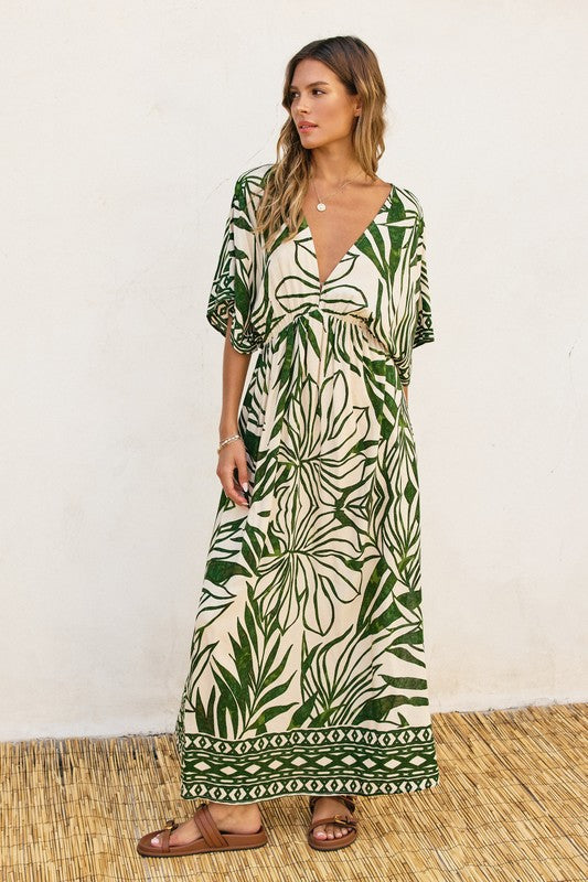 DOLMAN SLEEVE MAXI DRESS in a green graphic floral print on a natural background