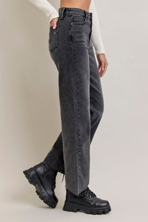 side view of Person wearing black high-waisted jeans and black boots on a plain background, wide leg, full-length, raw edge hem
