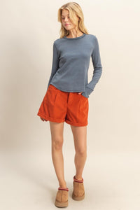 woman wearing mineral washed blue t-shirt with thumb hole long sleeves and reversed stitching around collar and shoulders, exposed seam down the back