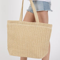 Beige woven tote bag held by a person wearing denim shorts on a white background