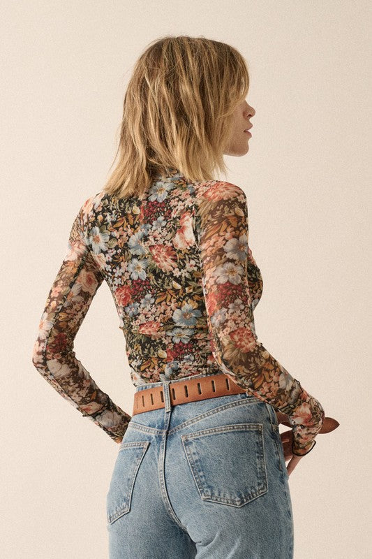 Floral print Semi-Sheer mesh top with long sleeves with thumbholes, a high neckline and
Ruffled Stitching at Hemline and wrist.  Bodice is lined.