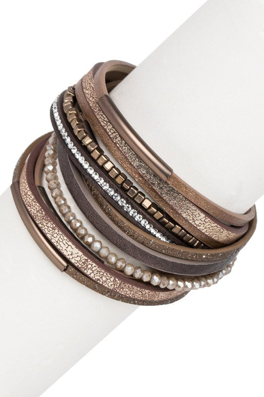Stack of brown leather bracelets with metallic accents on a white surface
