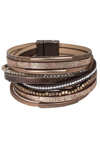 Stack of multistrand bracelets with metallic and leather textures on a white background
