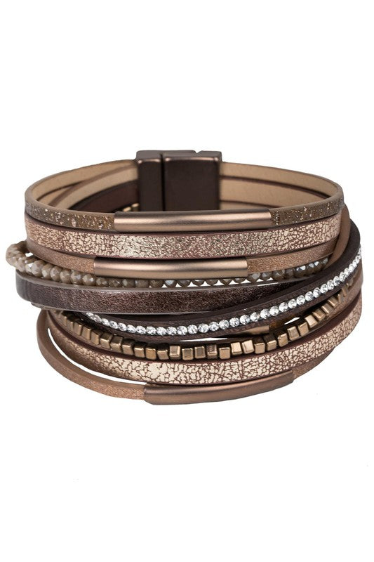 Stack of multistrand bracelets with metallic and leather textures on a white background