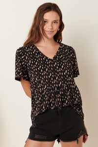 SHORT SLEEVE TOP WITH RUFFLE DETAIL in a geo print of rust and cream on black background